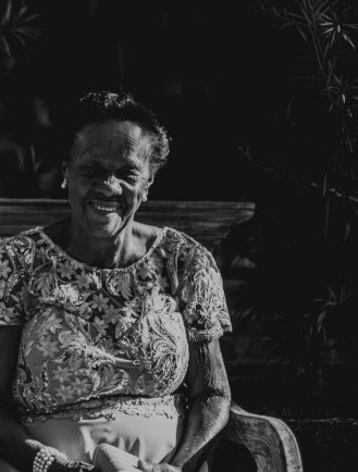 elderly woman sitting on bench in grayscale photography