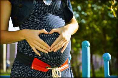 pregnant woman holding her tummy during daytime