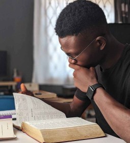 man wearing black crew neck shirt reading book